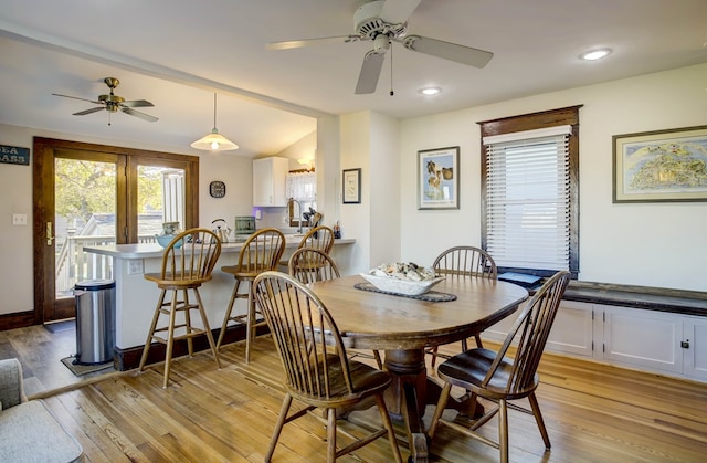 dining area featuring ceiling fan, sink, light hardwood / wood-style floors, and lofted ceiling