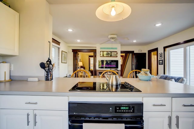 kitchen featuring black appliances, white cabinets, hanging light fixtures, ceiling fan, and kitchen peninsula