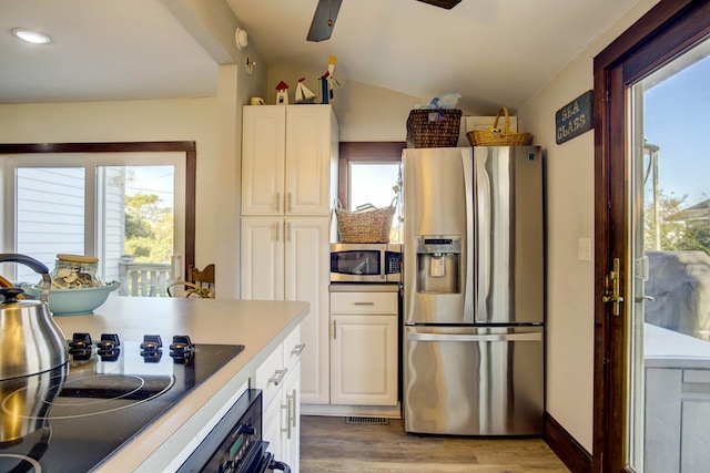 kitchen with white cabinets, appliances with stainless steel finishes, light hardwood / wood-style flooring, and a wealth of natural light