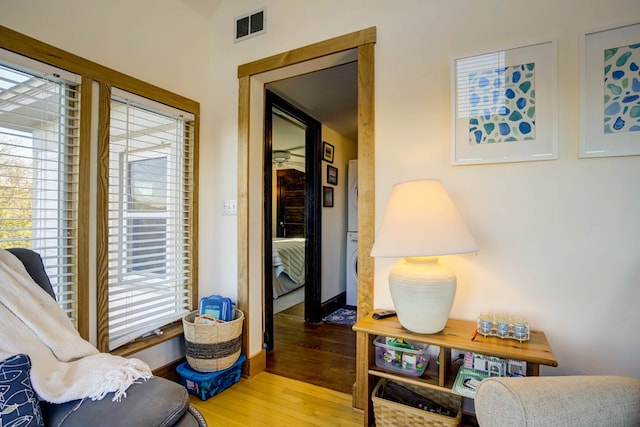 sitting room featuring light hardwood / wood-style floors and stacked washer and dryer