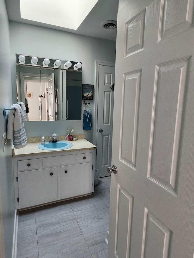 bathroom with tile patterned flooring, vanity, and a skylight