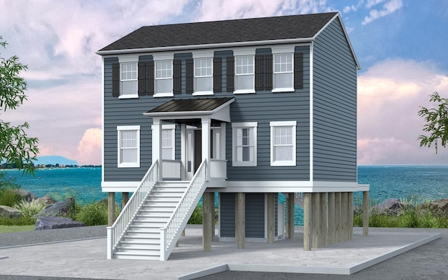 coastal inspired home with stairs, a shingled roof, and a water view