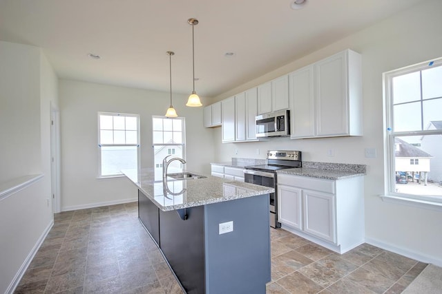 kitchen featuring stainless steel appliances, hanging light fixtures, a kitchen island with sink, white cabinets, and a sink