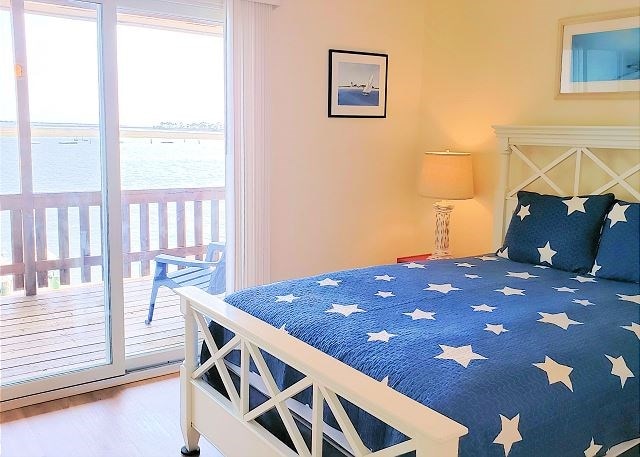 bedroom featuring hardwood / wood-style flooring, access to outside, and a water view