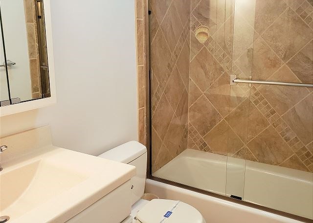 bathroom with enclosed tub / shower combo and toilet