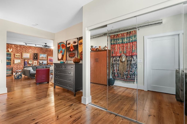 bedroom featuring hardwood / wood-style flooring, a closet, and brick wall