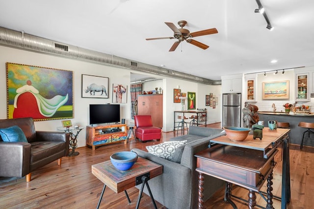 living room featuring ceiling fan, rail lighting, and hardwood / wood-style flooring