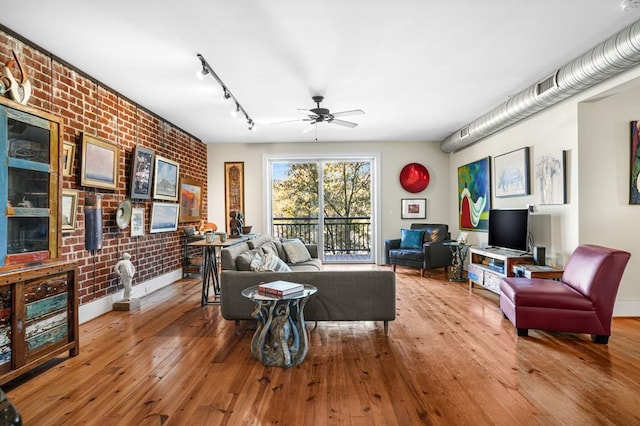 living room featuring ceiling fan, light hardwood / wood-style floors, and brick wall