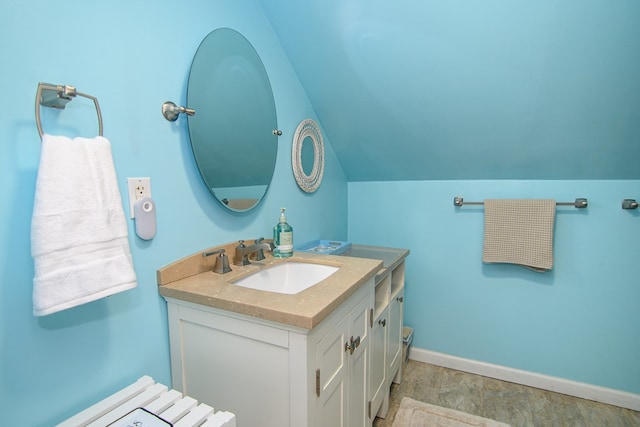 bathroom with baseboards, vaulted ceiling, and vanity