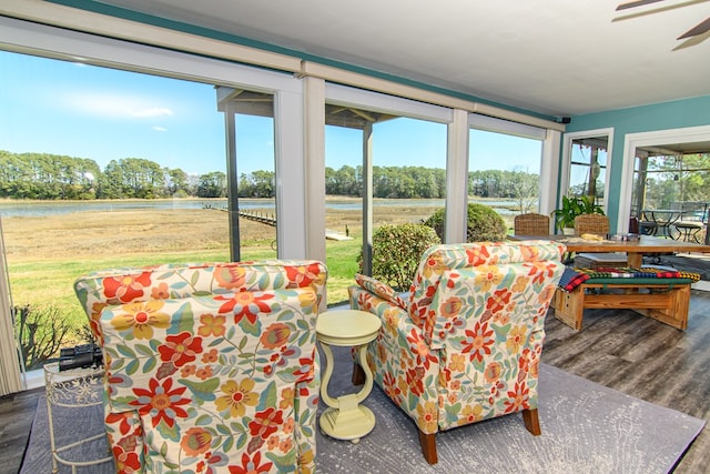 sunroom / solarium with a water view, outdoor dining area, wood finished floors, and ceiling fan
