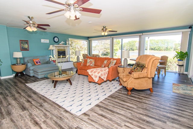 living area with baseboards, wood finished floors, a glass covered fireplace, and a ceiling fan