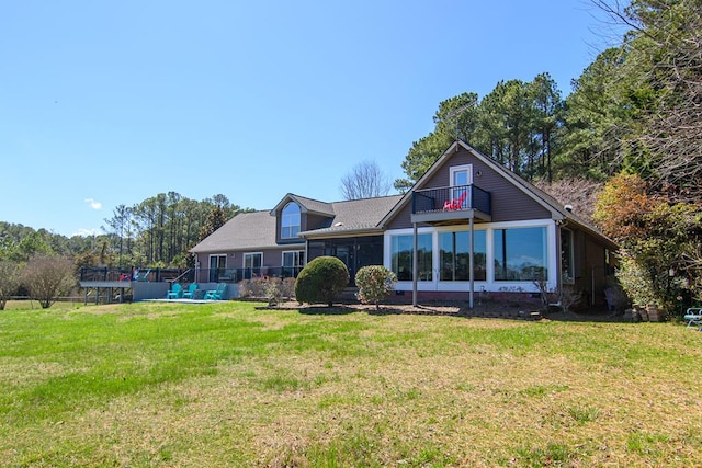 back of house with a balcony, a lawn, and a sunroom