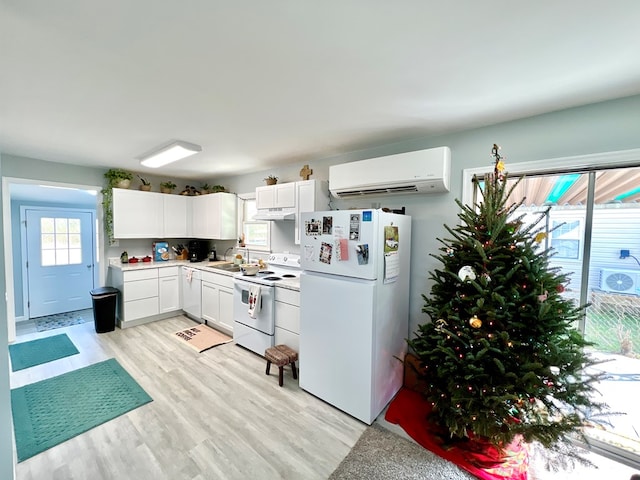 kitchen featuring white appliances, an AC wall unit, sink, light hardwood / wood-style floors, and white cabinetry