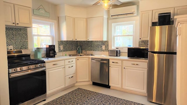 kitchen featuring a wall mounted air conditioner, appliances with stainless steel finishes, white cabinetry, and sink