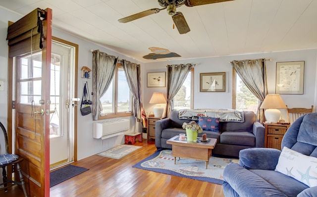 living room with a wall mounted AC, wood finished floors, and a ceiling fan