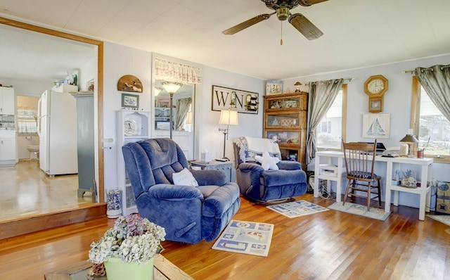 living area with wood-type flooring and ceiling fan