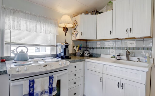 kitchen with backsplash, a sink, white electric range oven, and white cabinets