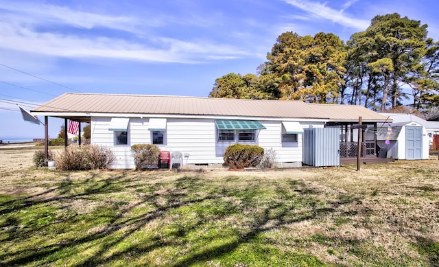 rear view of property with metal roof, an outdoor structure, a yard, crawl space, and a storage unit