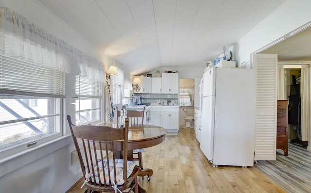 dining space featuring lofted ceiling and light wood-style floors