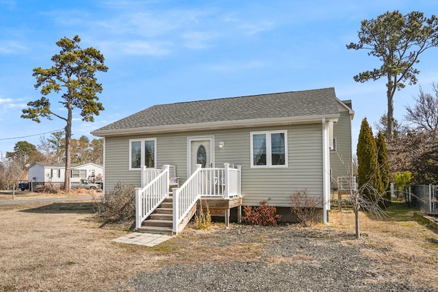 bungalow-style house with a shingled roof and fence