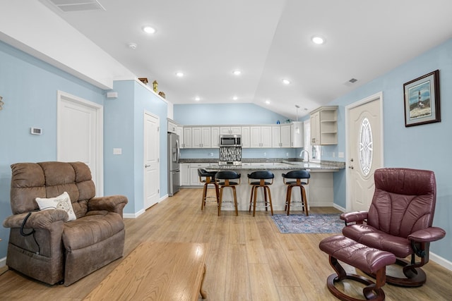 interior space with open floor plan, a peninsula, stainless steel appliances, light wood-style floors, and open shelves