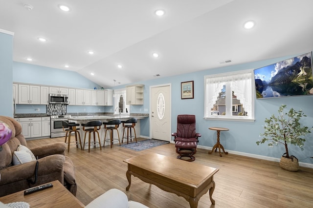 living area with lofted ceiling, visible vents, light wood finished floors, and recessed lighting