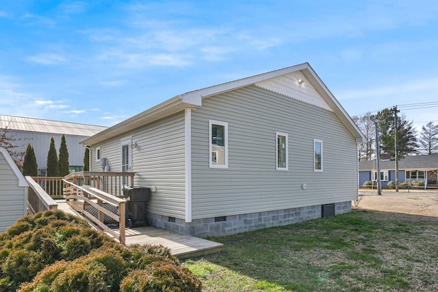 view of side of home with crawl space, a lawn, and a wooden deck