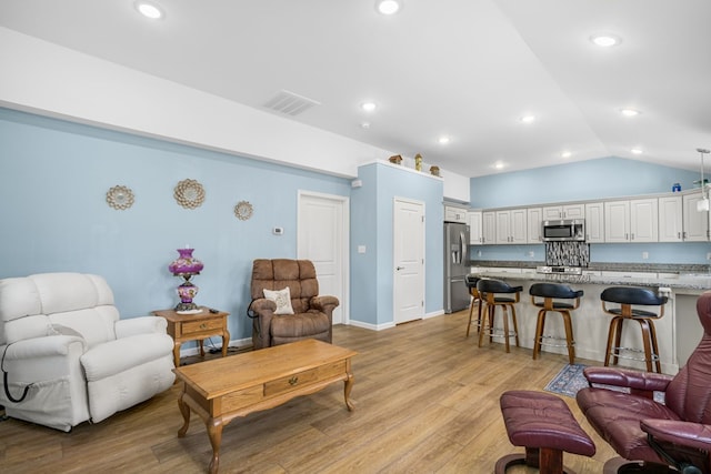 living area with light wood-style floors, visible vents, vaulted ceiling, and recessed lighting