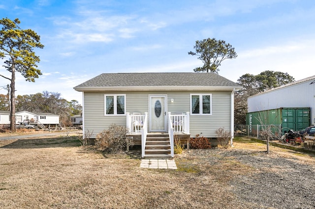 view of front of property with fence, a front lawn, and roof with shingles