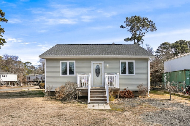 bungalow-style home with crawl space, a shingled roof, fence, and a front lawn