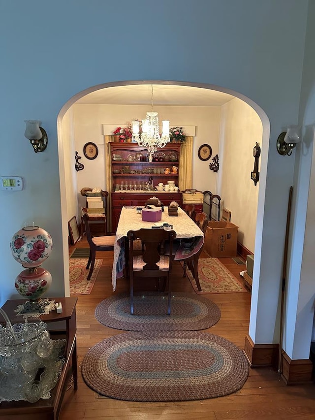3533 Ridge Rd, Chincoteague, VA 23336 - dining area with arched walkways, wood finished floors, a chandelier, and baseboards