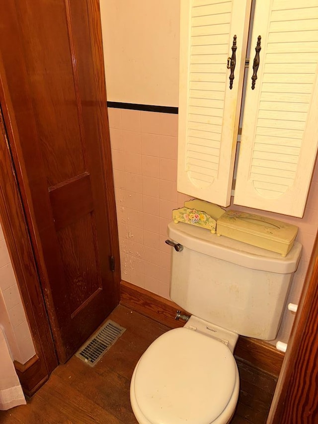 3533 Ridge Rd, Chincoteague, VA 23336 - bathroom with tile walls, toilet, wood finished floors, and a wainscoted wall