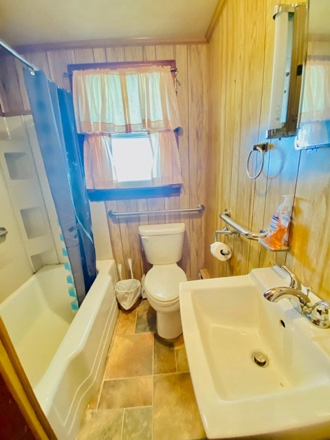 full bathroom featuring shower / bath combo with shower curtain, wood walls, toilet, and a sink