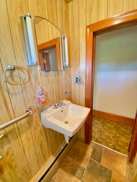 bathroom featuring wooden walls and a sink