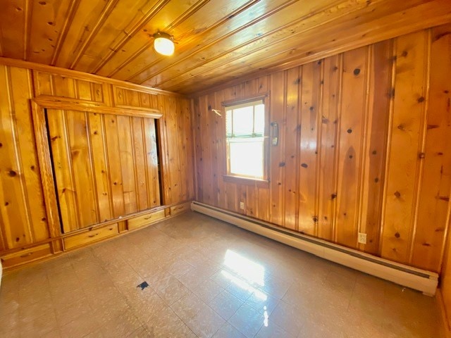 spare room featuring wood ceiling, a baseboard radiator, tile patterned floors, and wooden walls