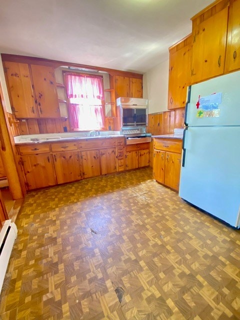 kitchen with open shelves, a baseboard heating unit, brown cabinets, wainscoting, and freestanding refrigerator