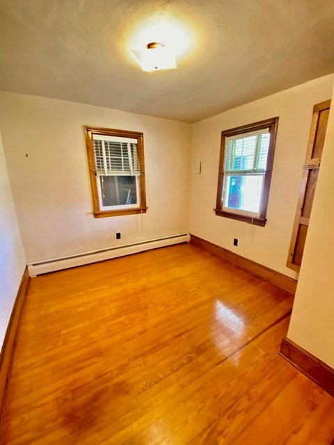 spare room featuring baseboards, baseboard heating, and wood finished floors