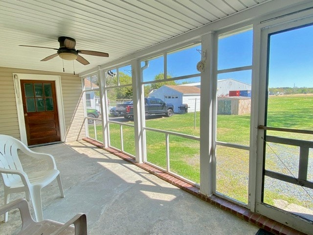 unfurnished sunroom featuring ceiling fan and a healthy amount of sunlight