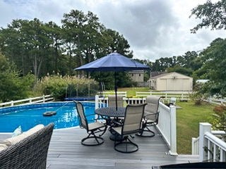 pool with a lawn, a deck, and fence