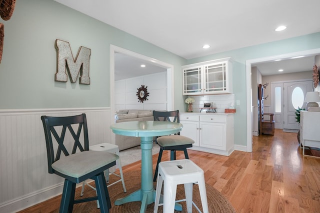 dining space featuring recessed lighting, wainscoting, and light wood finished floors