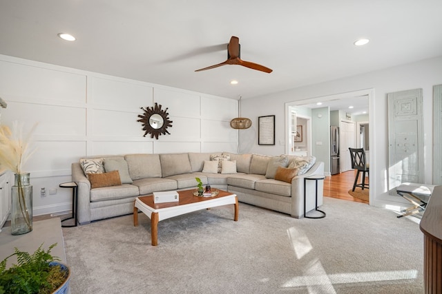 living area with a decorative wall, recessed lighting, and ceiling fan