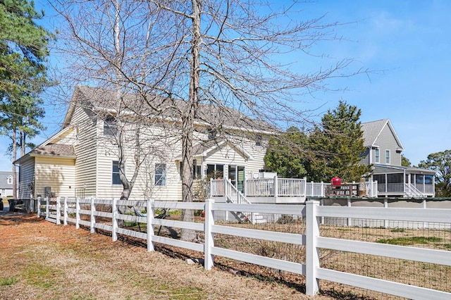 view of front of home featuring a fenced front yard, a shingled roof, and a sunroom
