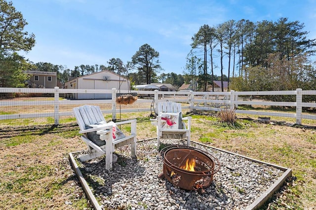 view of yard featuring an outdoor structure, a fire pit, and fence
