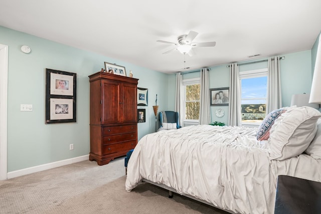 bedroom featuring visible vents, baseboards, light colored carpet, and a ceiling fan