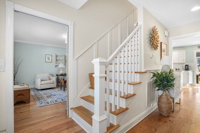 stairs featuring visible vents, ornamental molding, baseboards, and wood finished floors