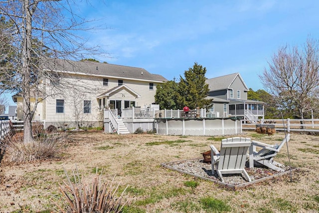 back of property featuring stairway, a fenced in pool, a wooden deck, a fenced backyard, and a sunroom