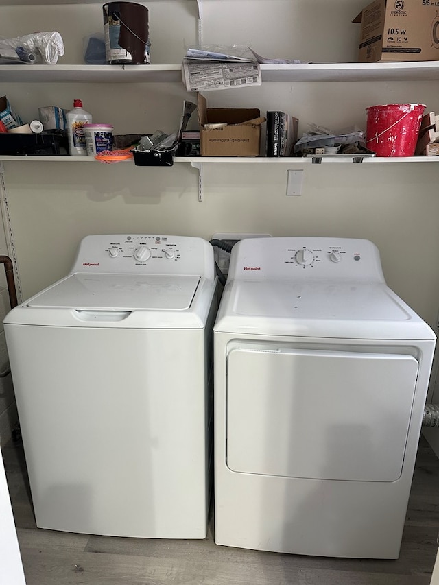 laundry room with wood-type flooring and washing machine and clothes dryer