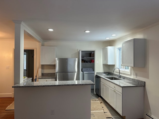 kitchen featuring sink, appliances with stainless steel finishes, white cabinetry, stone countertops, and washer / clothes dryer