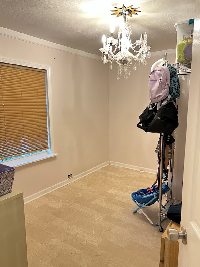 exercise room with a textured ceiling, baseboards, wood finished floors, and an inviting chandelier