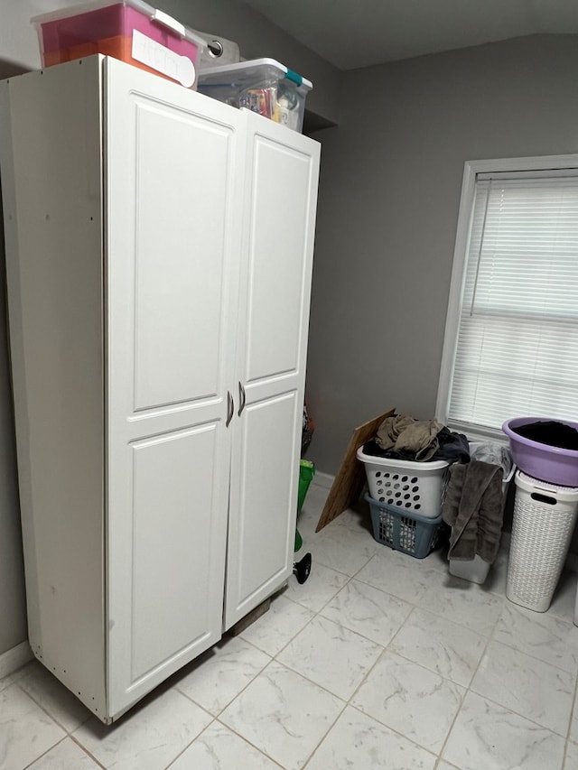 laundry room featuring marble finish floor and baseboards